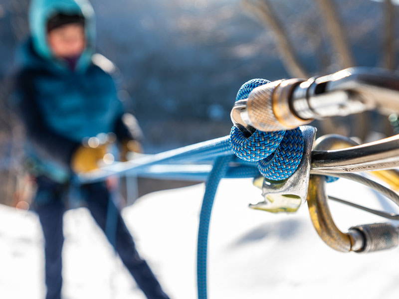 close-up view of steel carabiners attached to Sterling climbing rope, with climber in background
