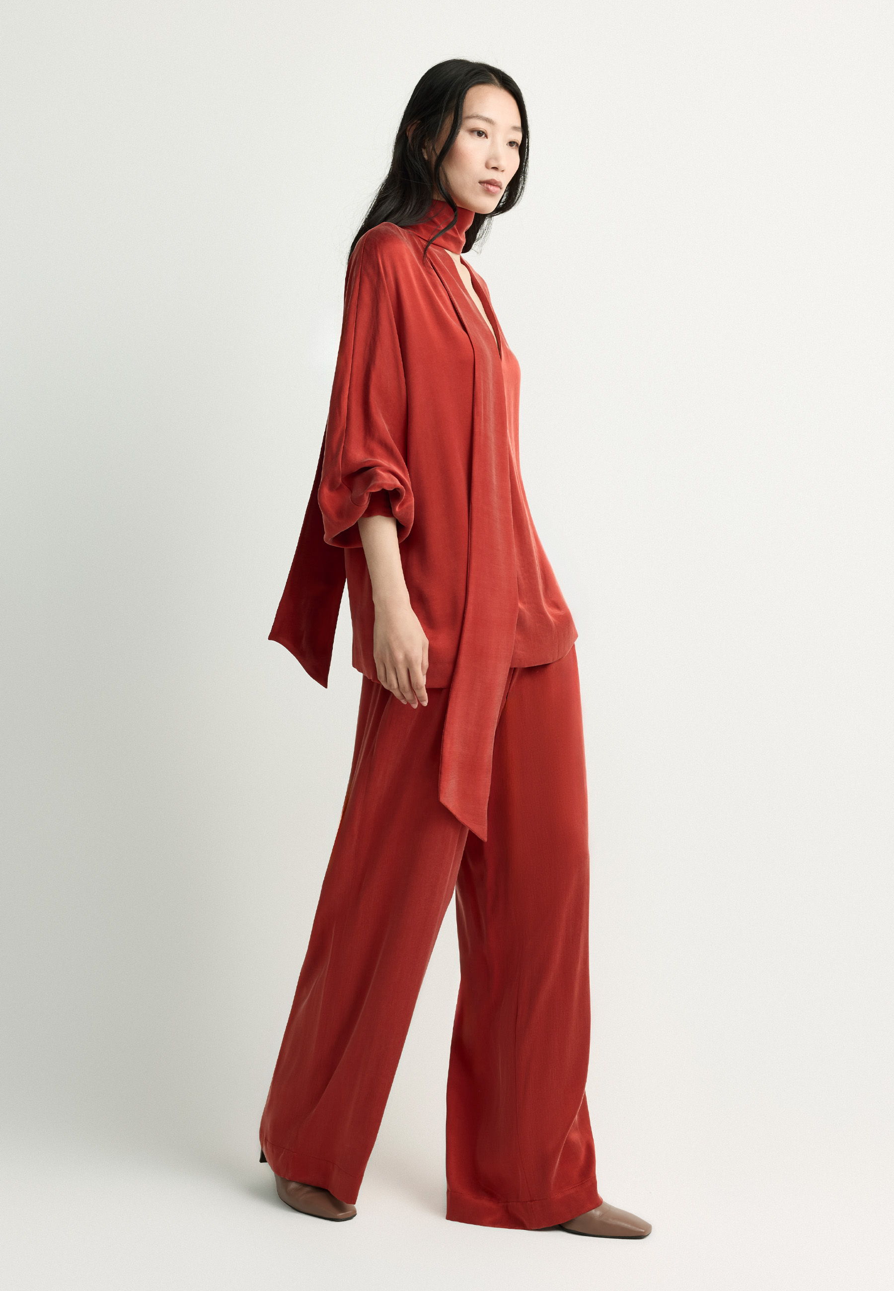 Woman wearing a stylish red outfit, standing against a neutral background.