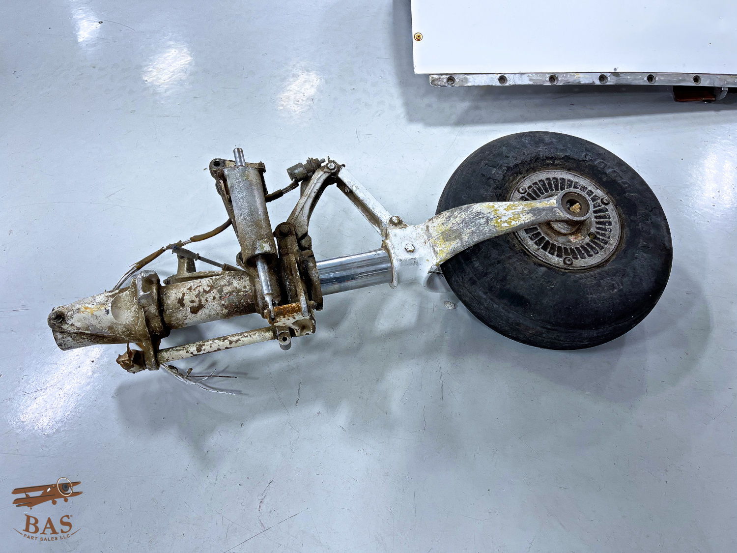 Aircraft landing gear assembly with a wheel on a smooth surface.