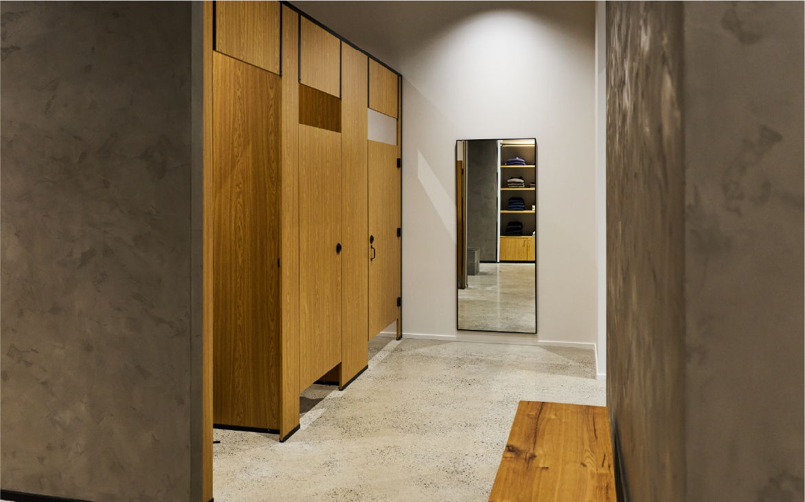 Interior of a modern changing room with wooden lockers and a mirror.