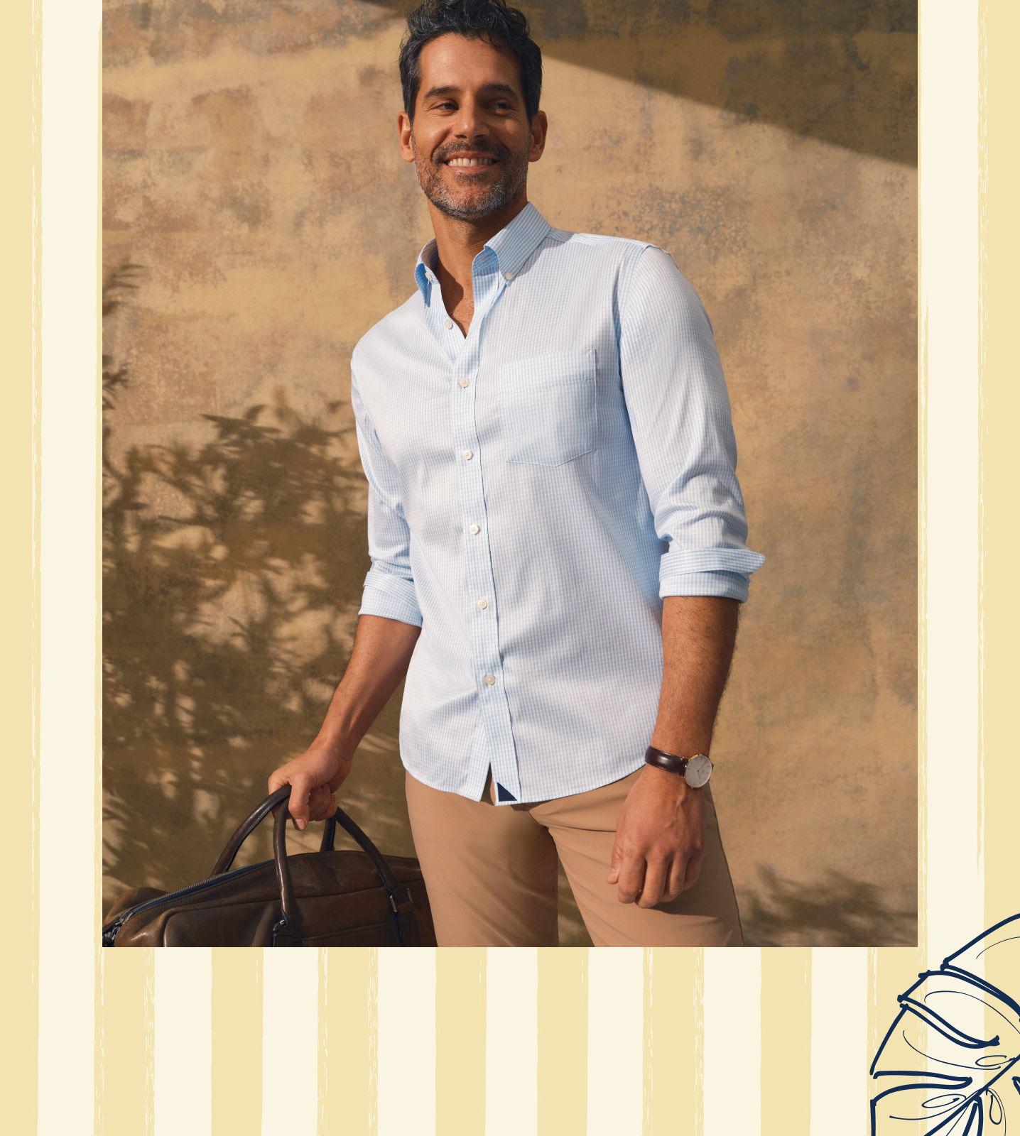Man in a light blue shirt holding a bag, smiling outdoors.