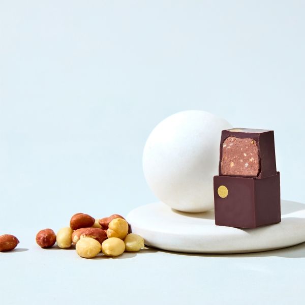 Chocolate treat beside an egg and assorted nuts on a plate.