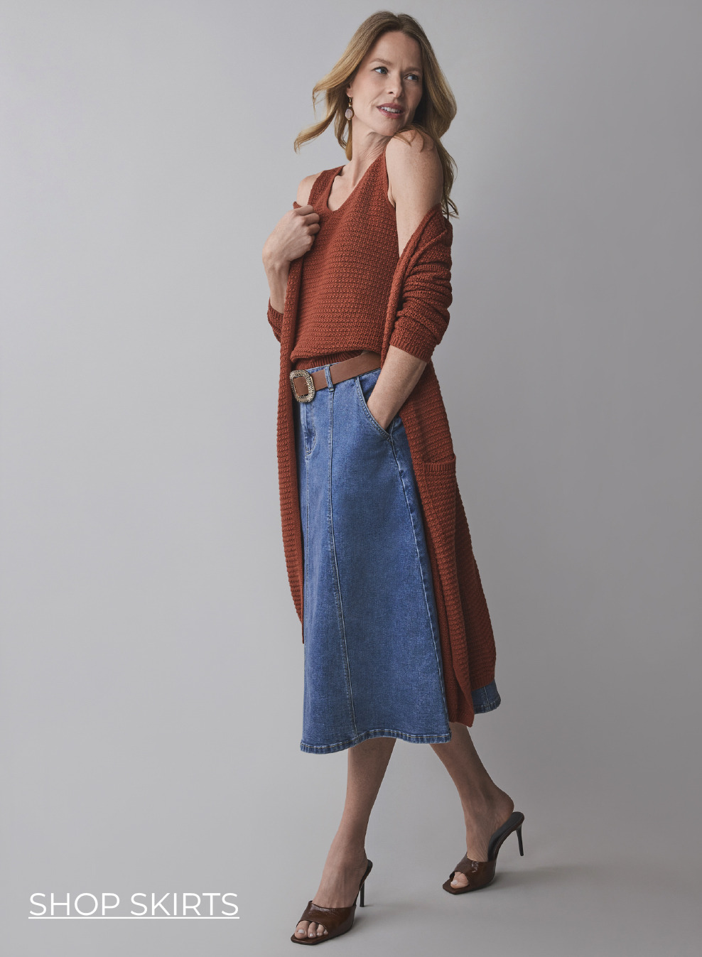 Woman in casual outfit with a long cardigan and denim skirt.