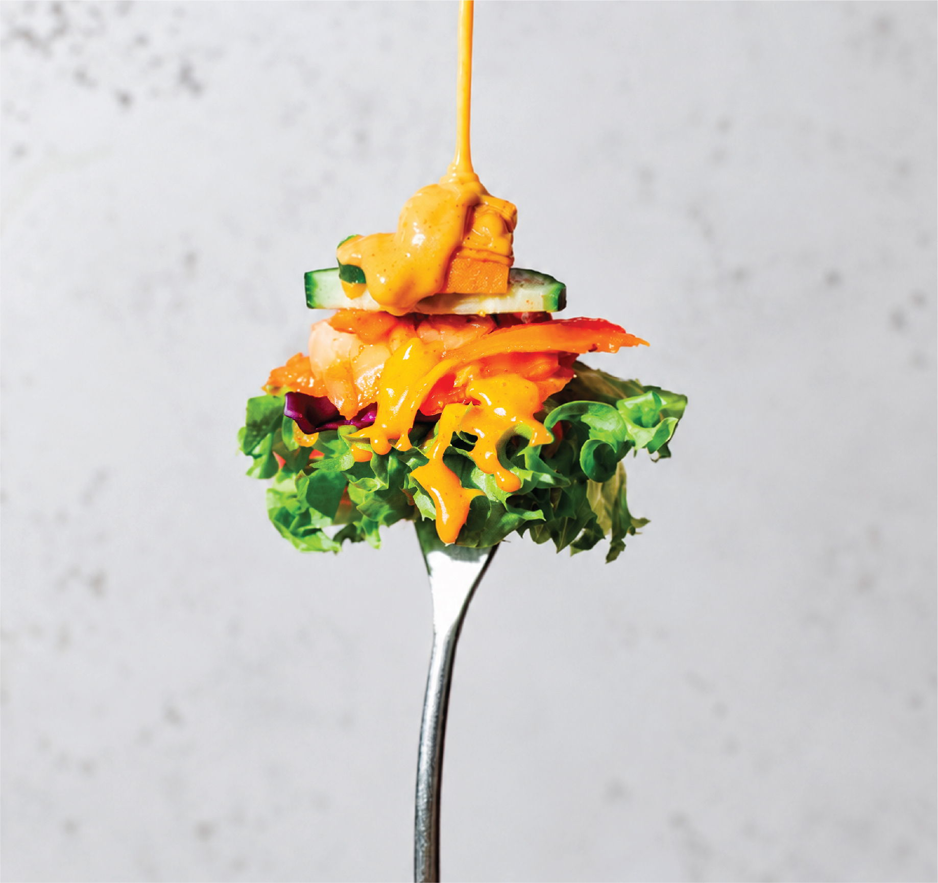 A fork holding a colorful salad with various vegetables.