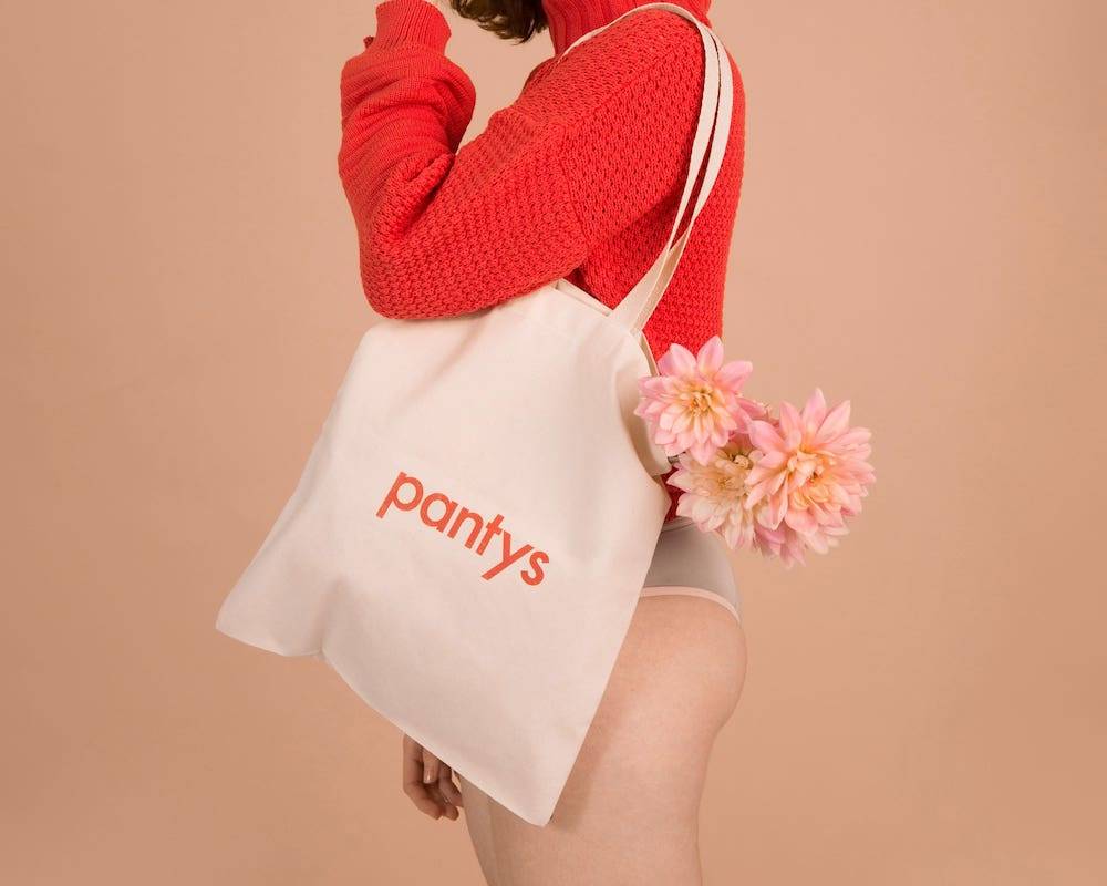 Fotografia de mulher de perfil com sacola da pantys com flores