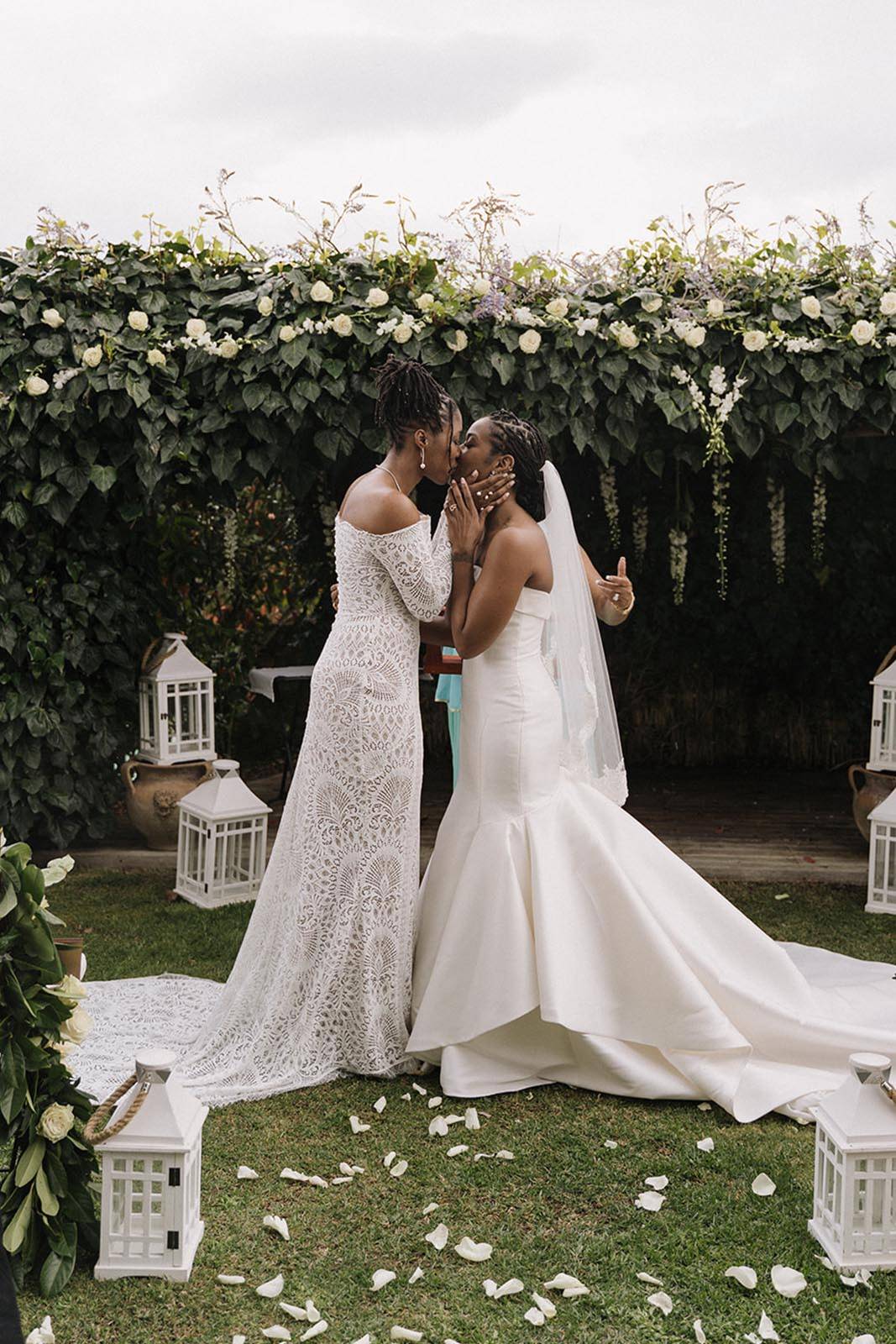Two brides, sharing a kiss in the garden