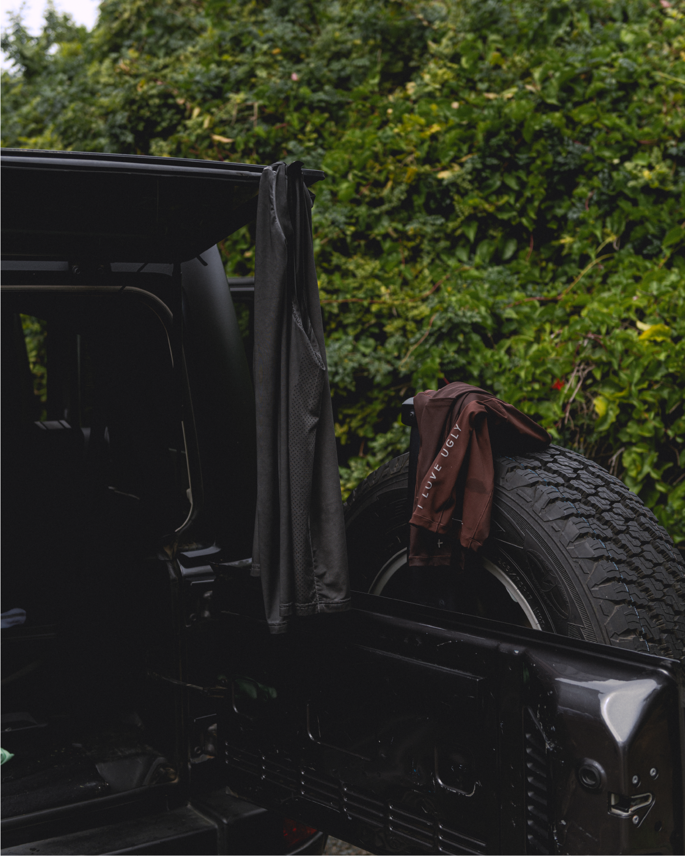 A black vehicle with a tire and clothing hanging out.