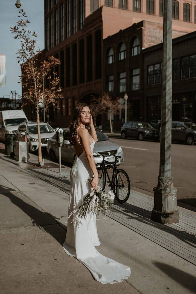 Novia con vestido de seda de espalda baja en las calles de Denver