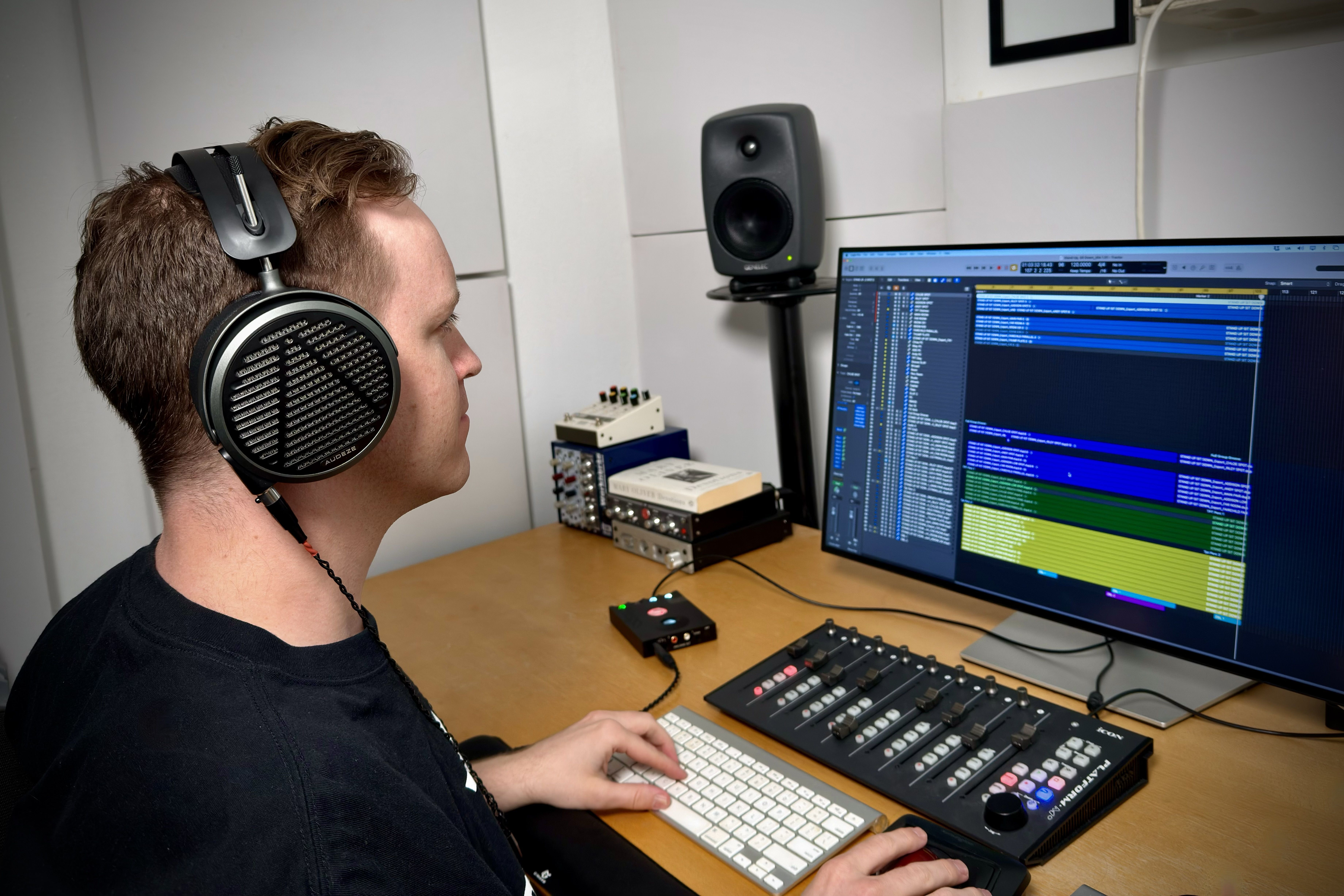 Andy Clausen wearing Audeze MM-500 headphones working on music production software at a computer.