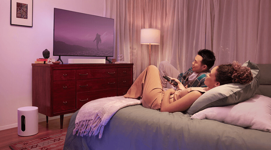 A couple relaxing on a bed, watching TV in a cozy room.