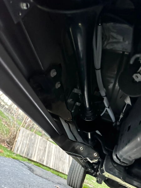 Close-up undercarriage view of black train horn mounted with white air lines routed along frame