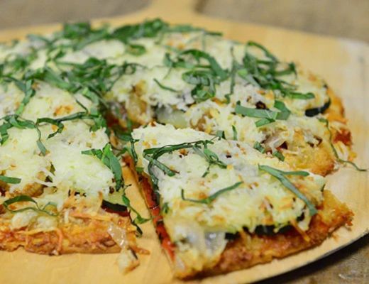 A freshly baked pizza topped with cheese and herbs, partially sliced.