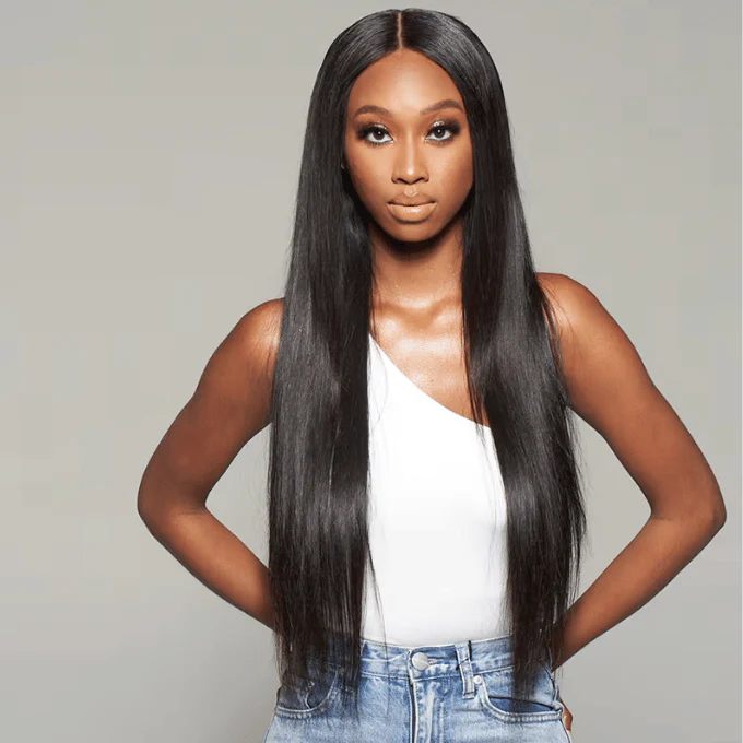 A woman with straight hair extensions wearing a white top and jeans.