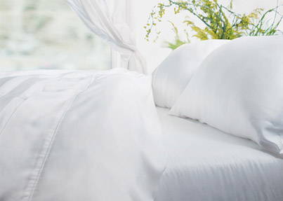 Weiße Perkalbettlaken auf einem Bett