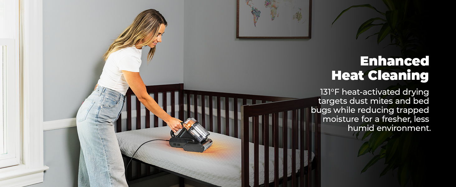 Woman cleaning a crib with a mattress vacuum in a well-lit room. Text about enhanced heat cleaning.