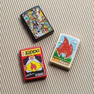 Three Comic design lighters, laying on pinstripe background