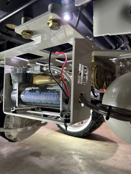 Close-up of HornBlasters air compressor in custom white HB-logo bracket under vehicle