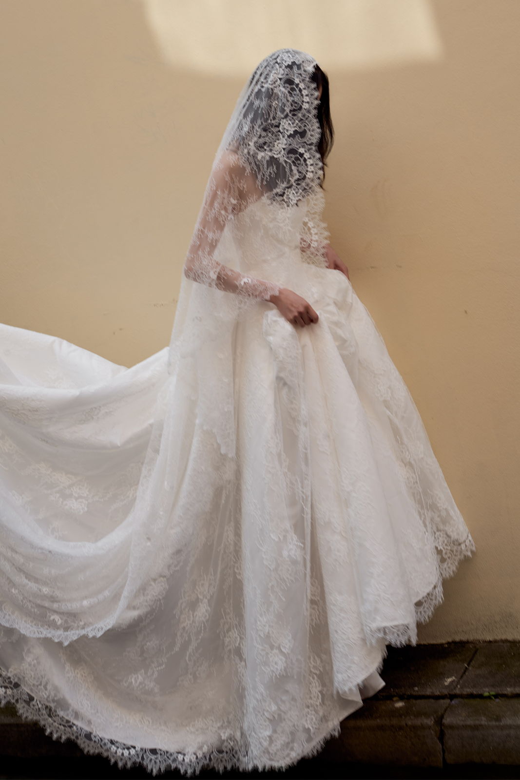 A bride in a white lace wedding dress and veil.