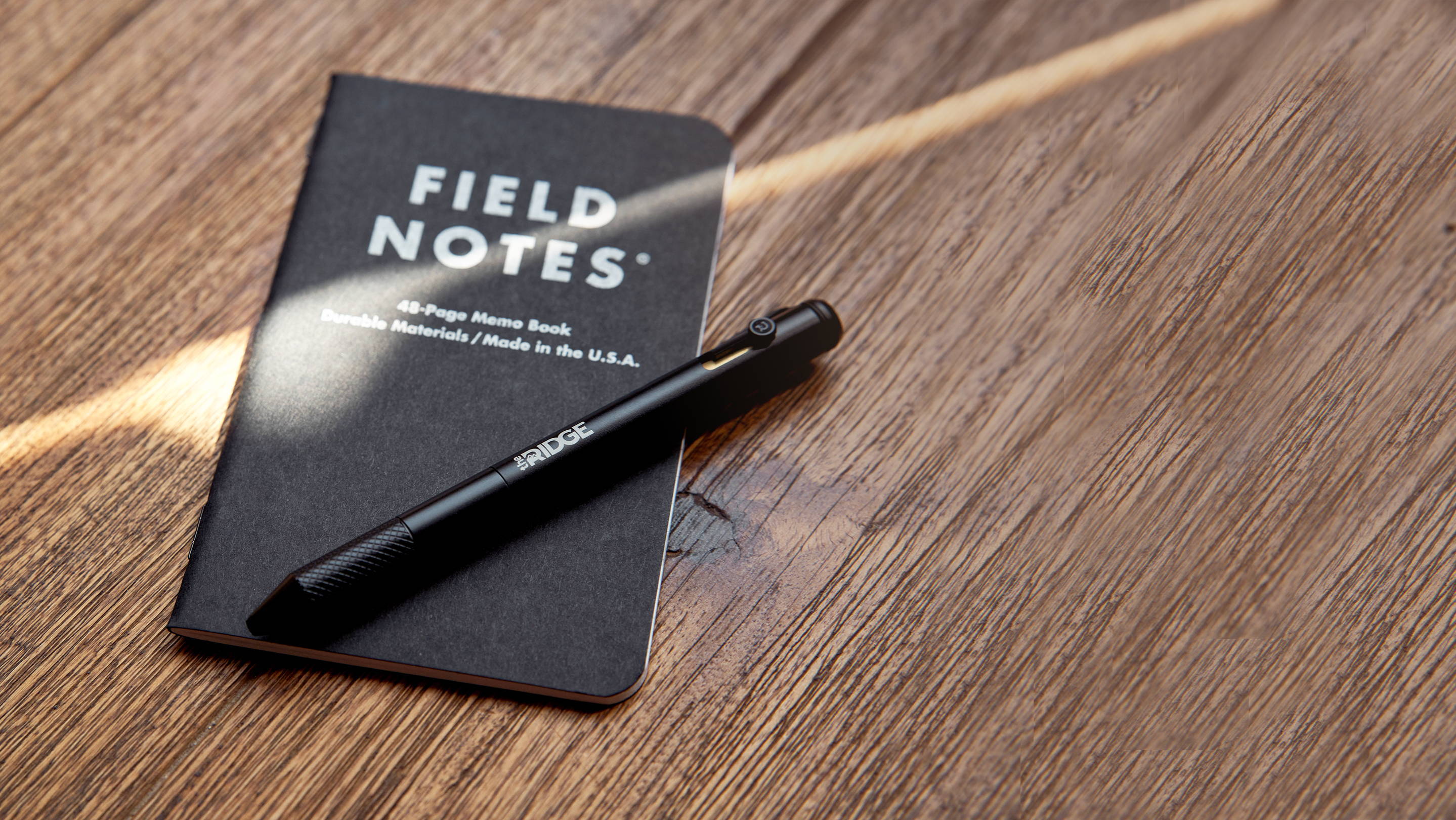 Matte Black Titanium Bolt Action Pen and Ridge Field Notes on wooden top