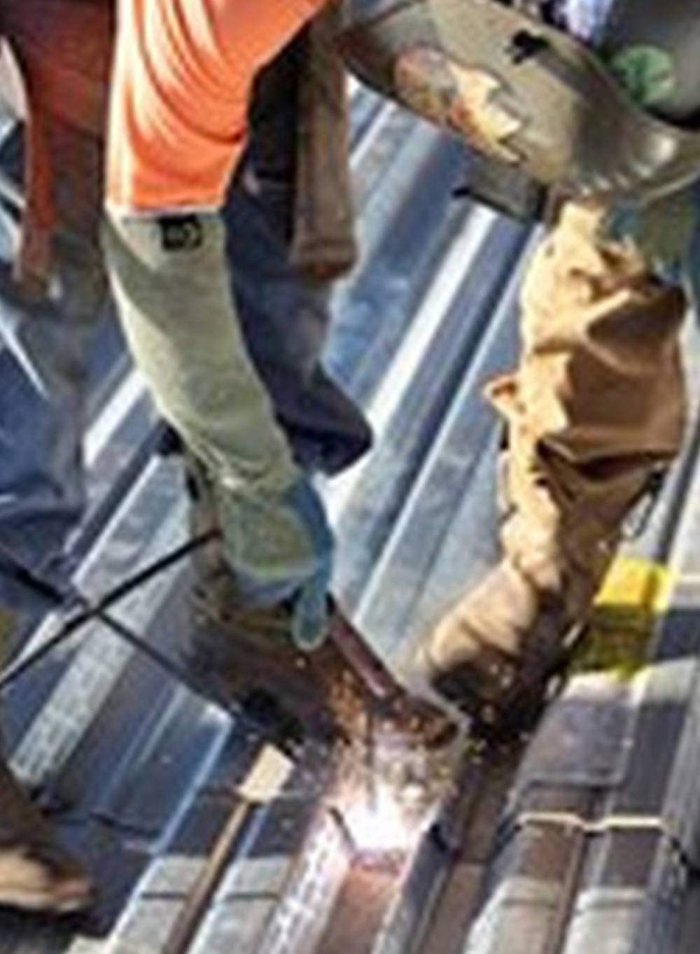 Construction worker wearing kevlar cut resistant sleeves and gloves while cutting sheet metal.
