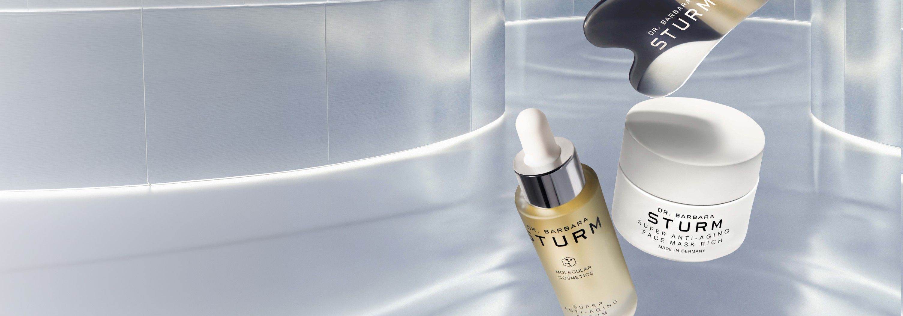 A serum and cream floating against a sleek, reflective background.