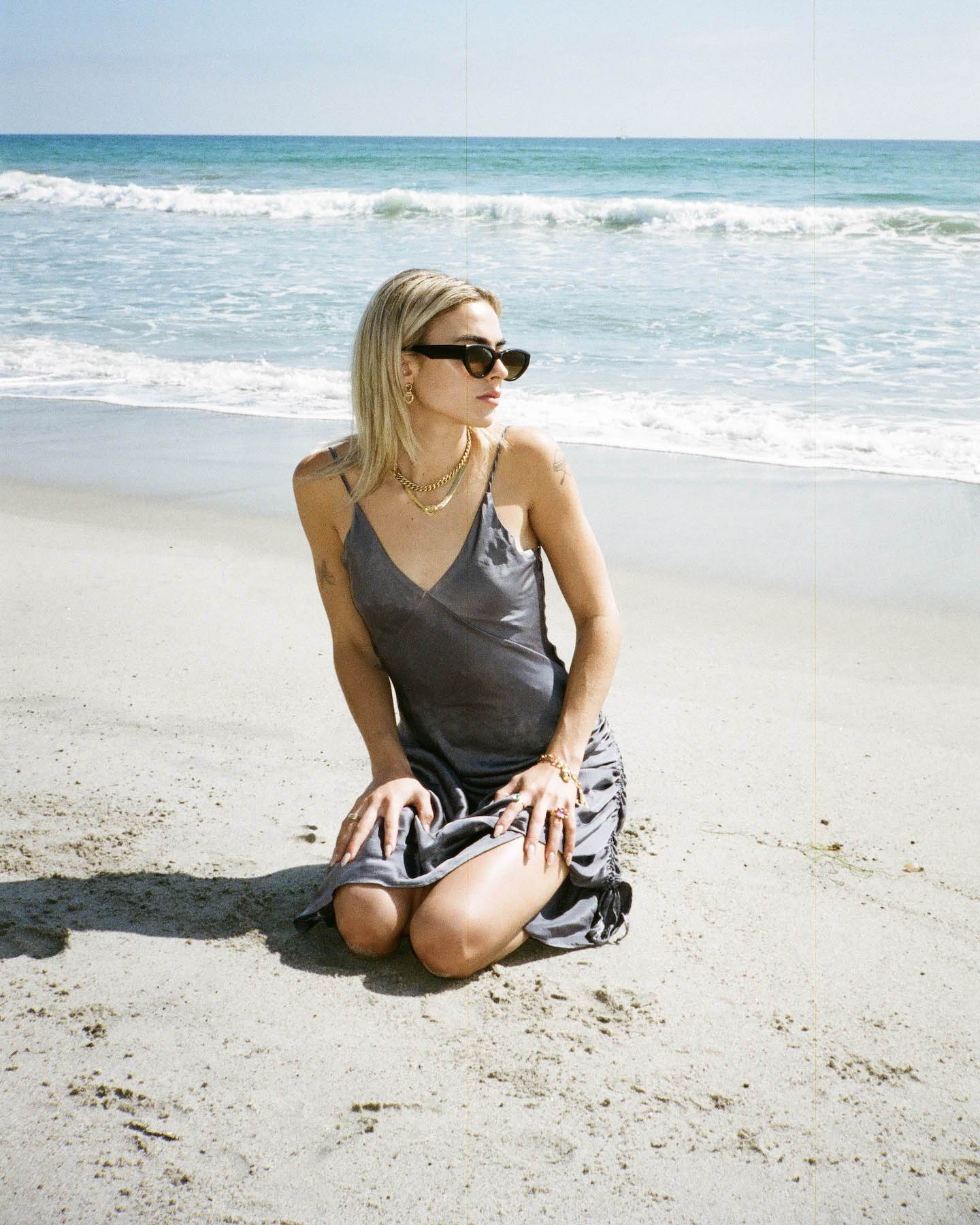 Image of model on the beach wearing SVNR dress with Laura Lombardi and Mondo Mondo jewelry.