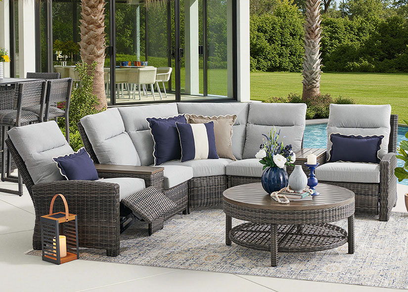 Outdoor seating area with a sectional sofa and coffee table by a pool.