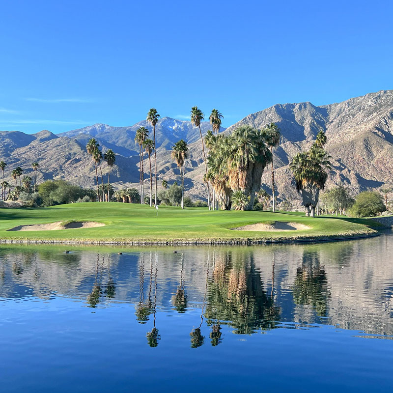 Palm Springs golf course with lake and mountains in background.
