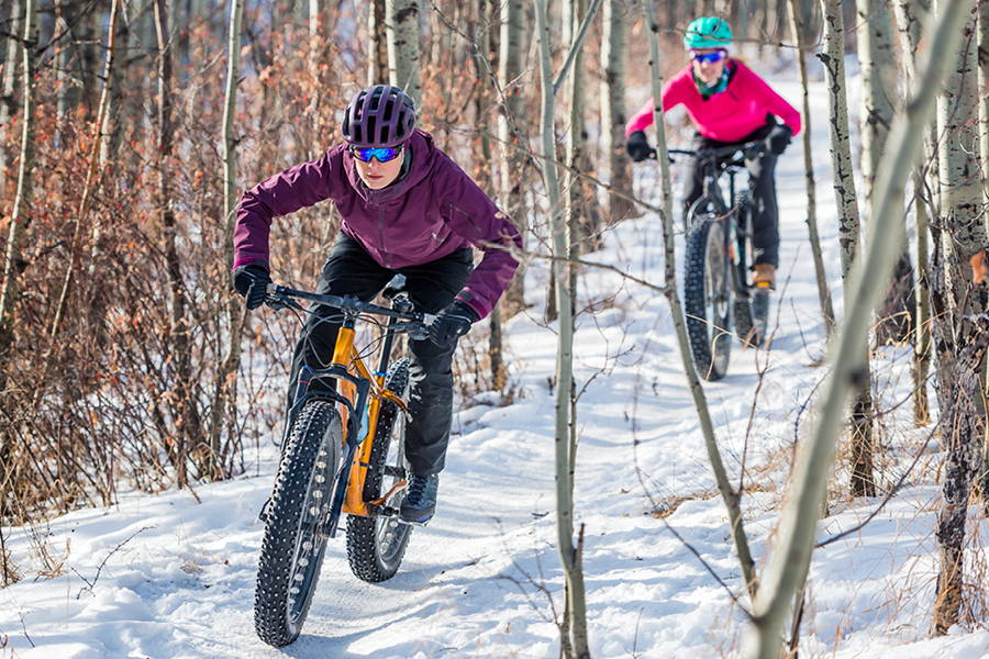 2 women winter biking on snowy trail