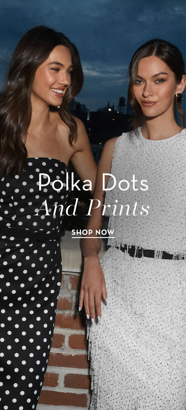 Two women in stylish polka dot outfits against a city skyline backdrop.