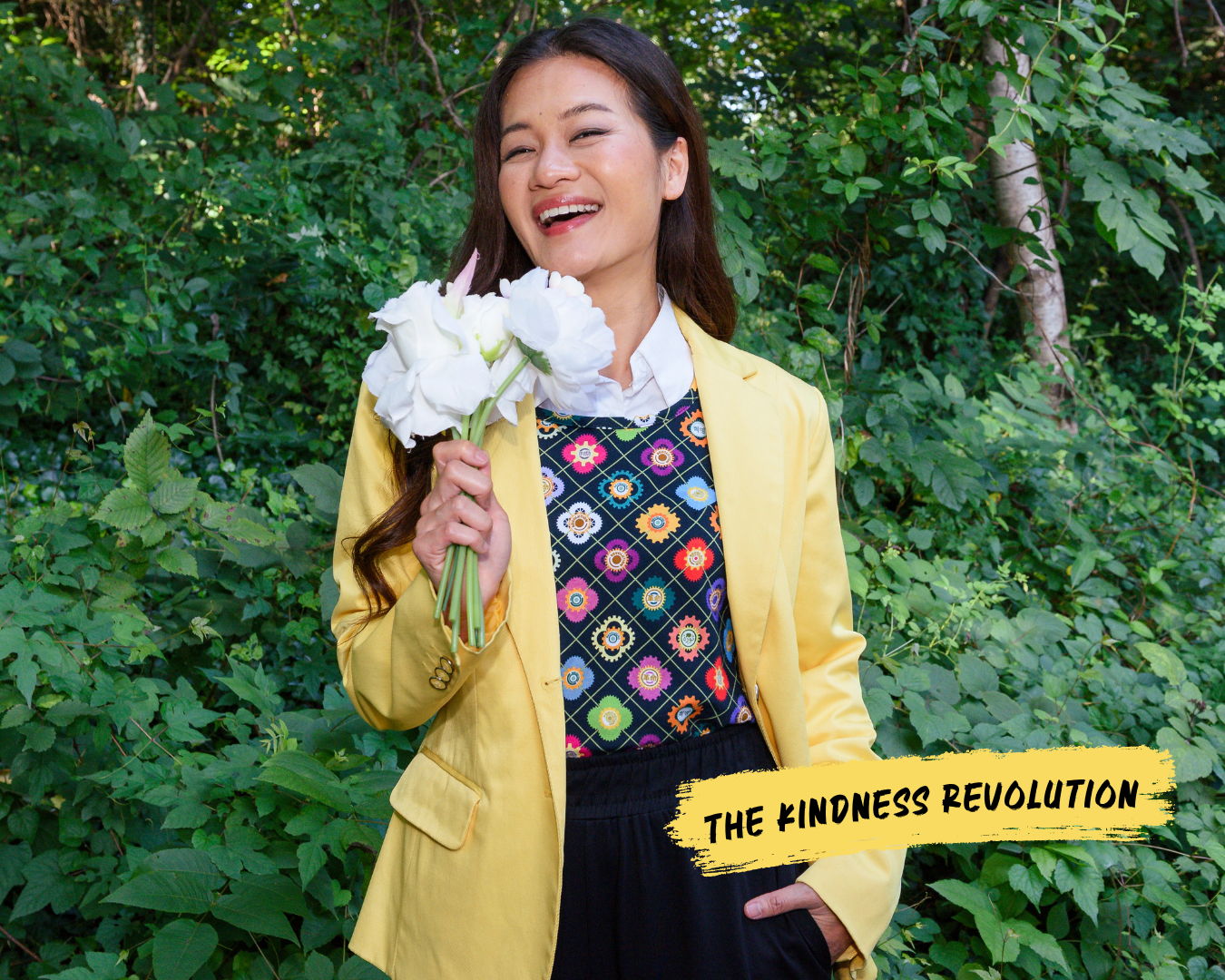 Women smiles holding flowers while wearing the Gears of Revolution print, standing for the kindness revolution