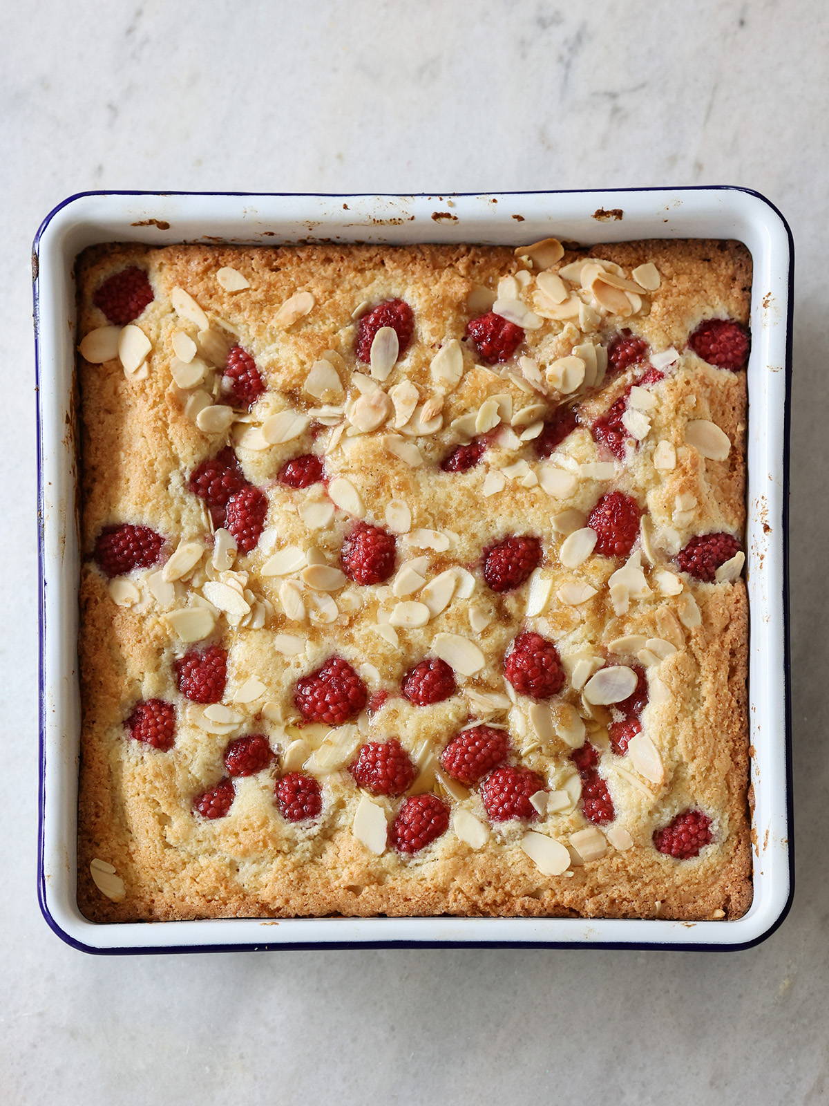 A photograph of a Raspberry Frangipane Bake in a Square bake tray.