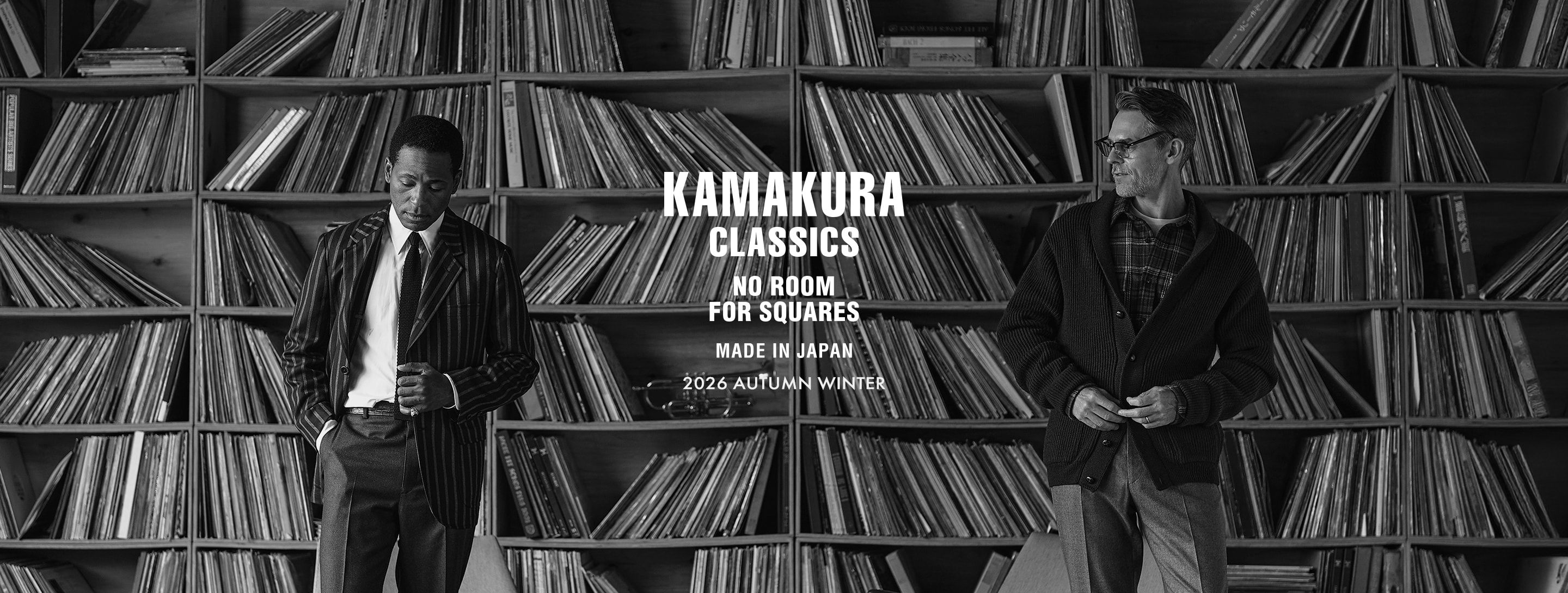 Two men standing in front of a bookshelf filled with records.