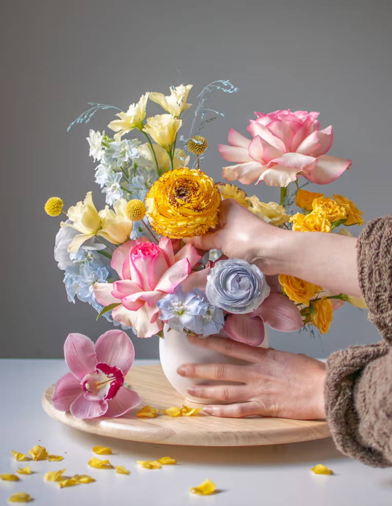 Close crop of someone's hands as they arrange a fluffy spring-like floral arrangement 