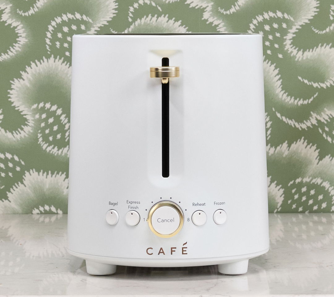 White toaster with gold accents against a floral green background.