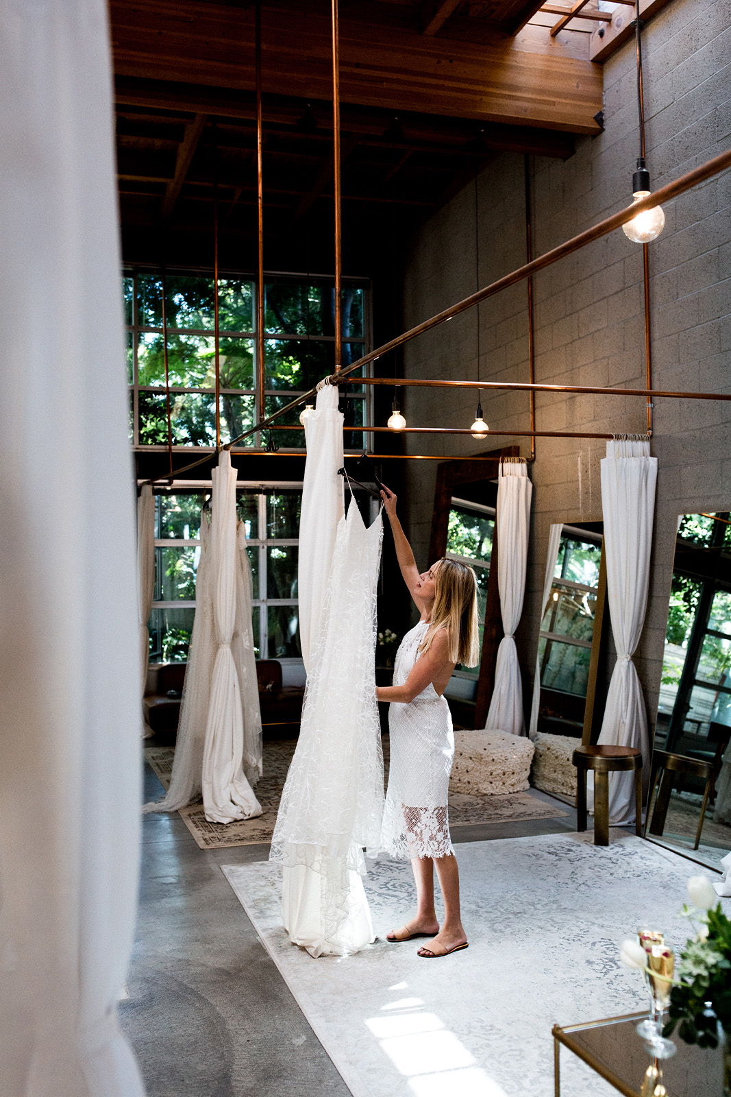 A woman adjusts a wedding dress in a stylish, modern interior.