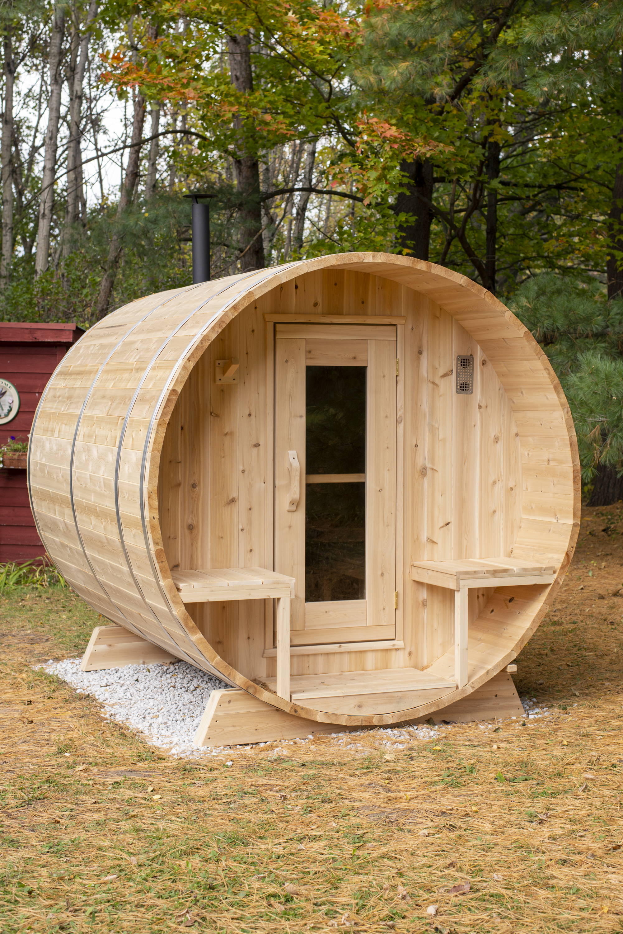 Barrel sauna on gravel, in wooded area
