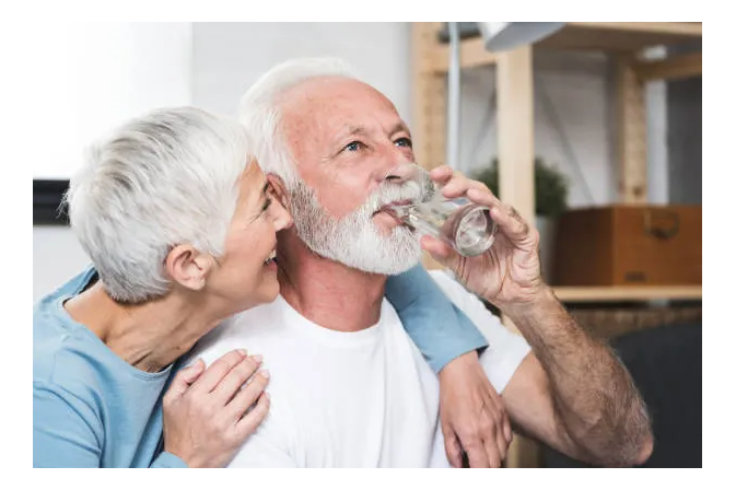 happy older woman with older man drinking glass of water 