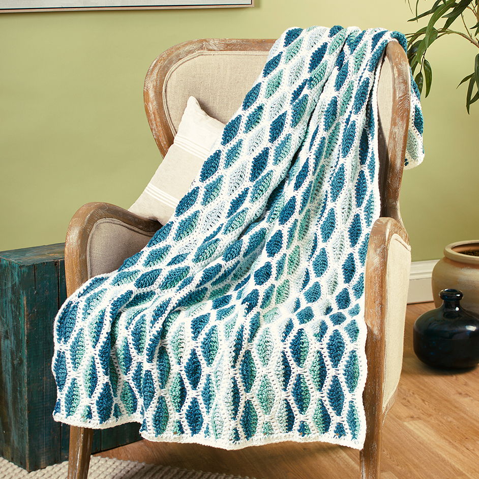A patterned blanket draped over a chair in a cozy setting.