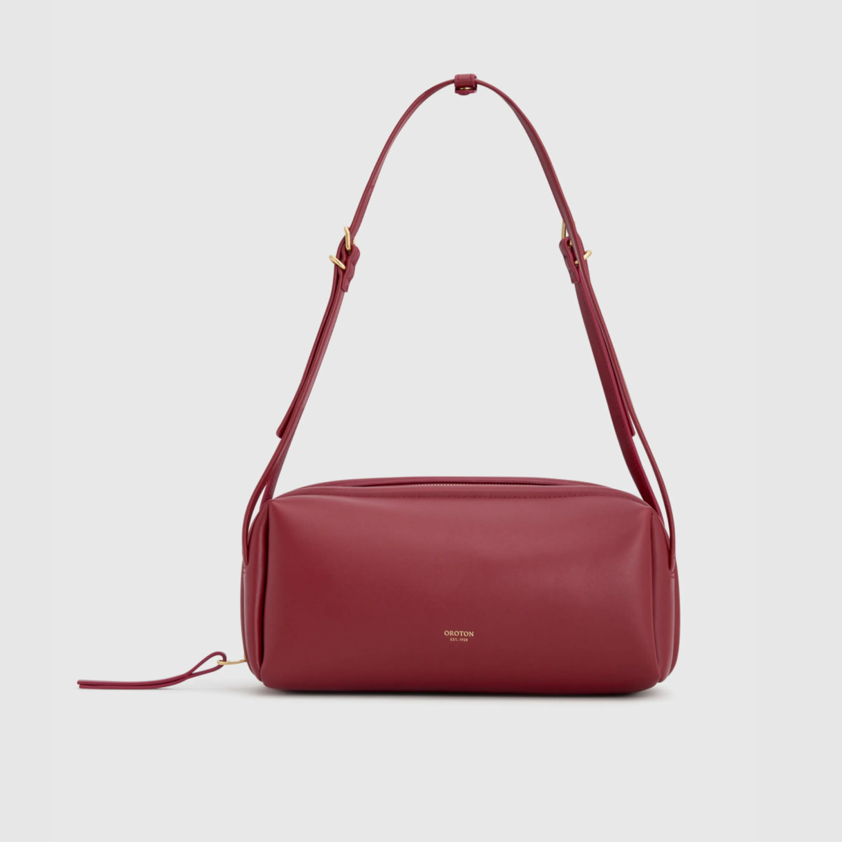 Red shoulder bag with a long strap on a plain background.