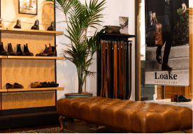 Shoes and belts displayed in a stylish retail space with a leather bench.