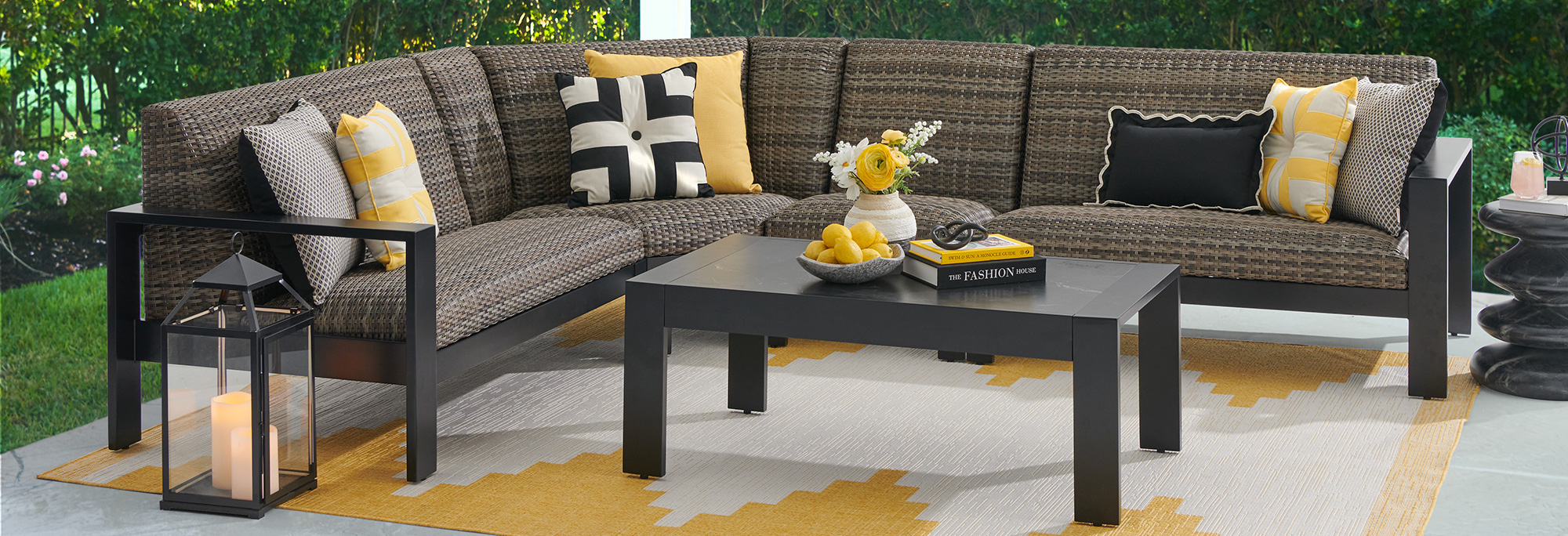 Outdoor sectional seating with cushions and a coffee table on a patterned rug.