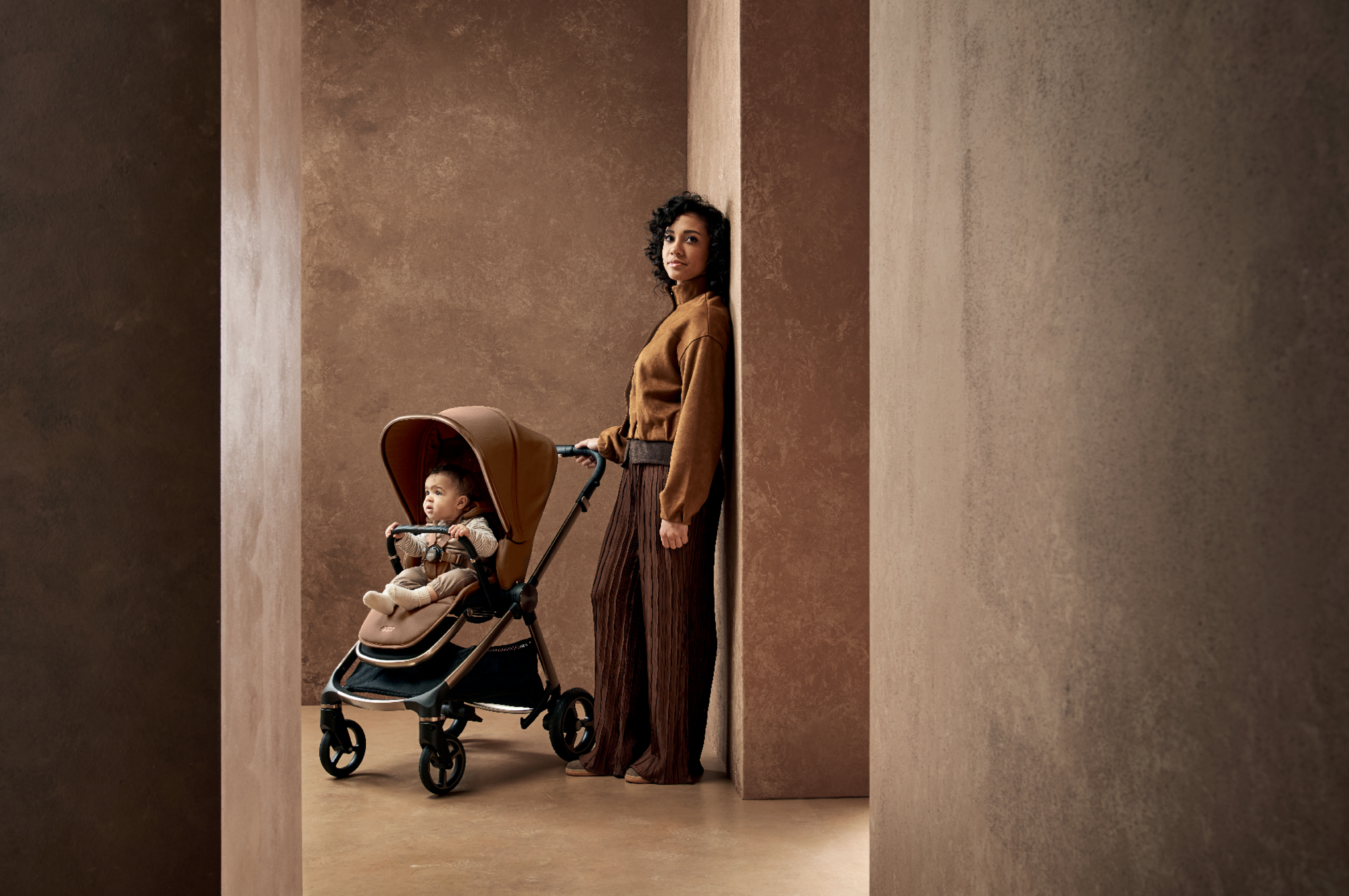 Woman standing beside a stroller with a child in a modern interior.