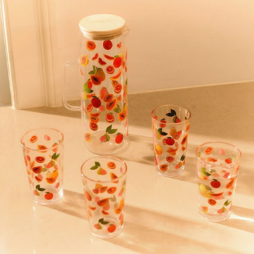 Colorful glass pitcher and cups with fruit designs.