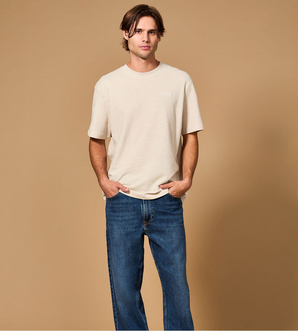 GUESS model standing in casual attire against a neutral background.