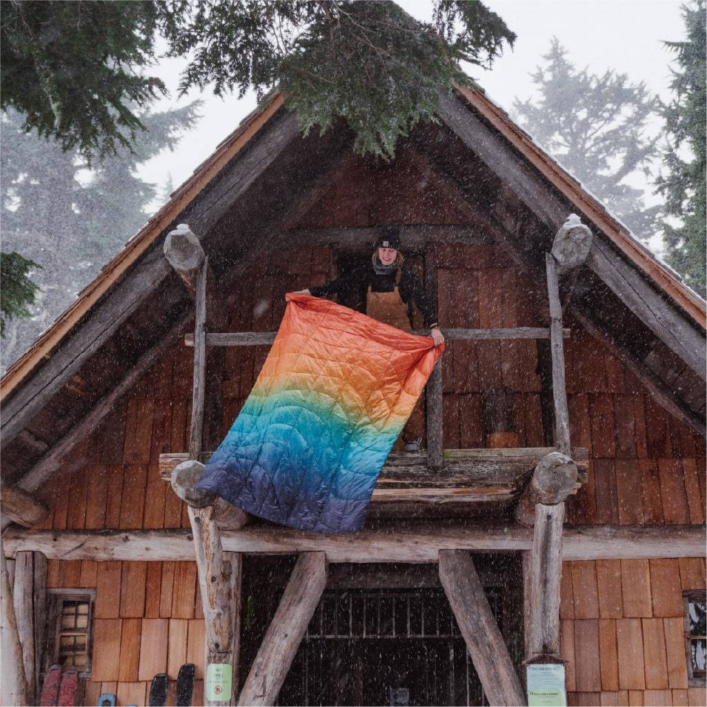 Woman with rainbow blanket in wooden A frame