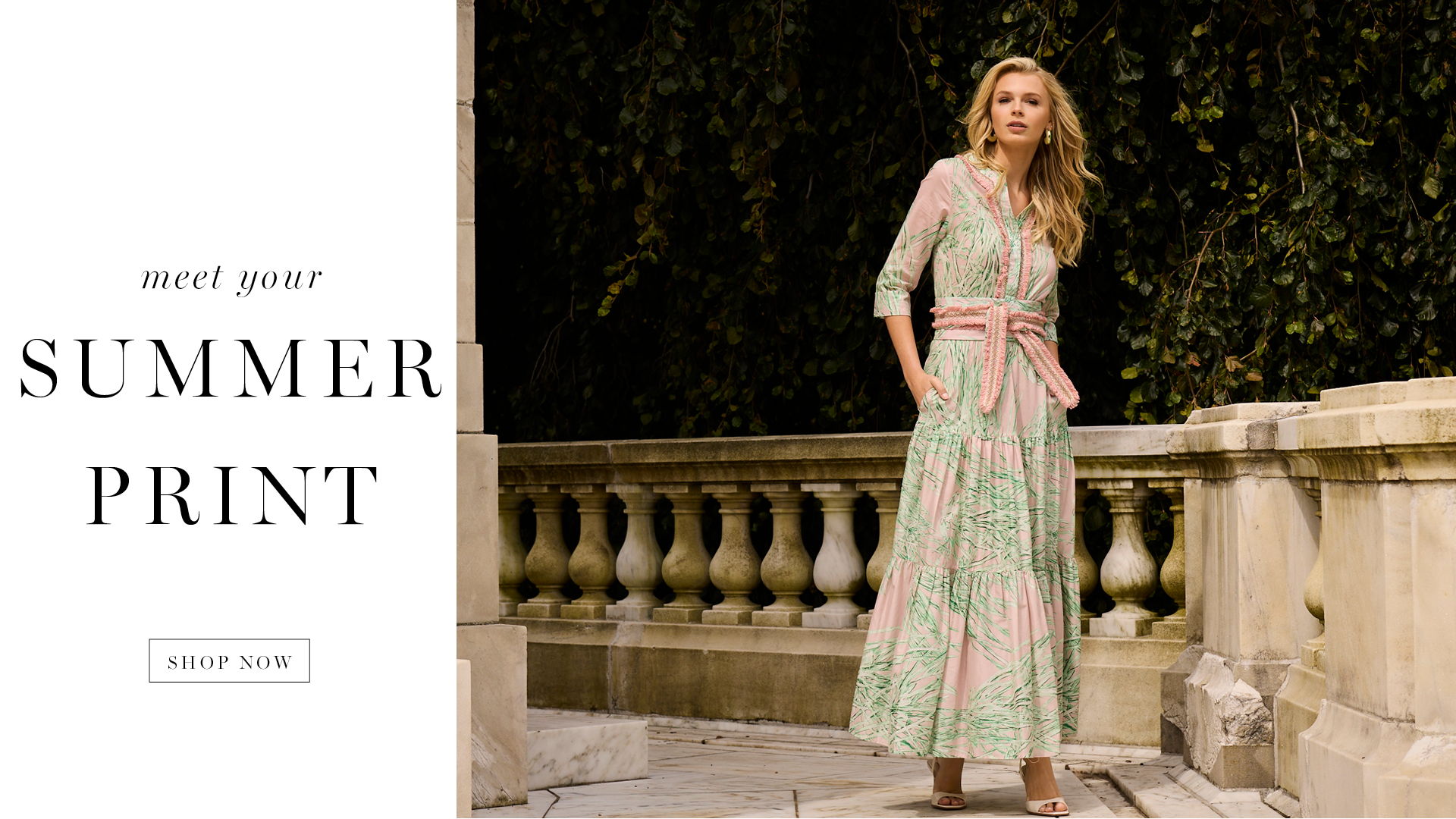 A model in a summer print dress poses near a decorative wall.