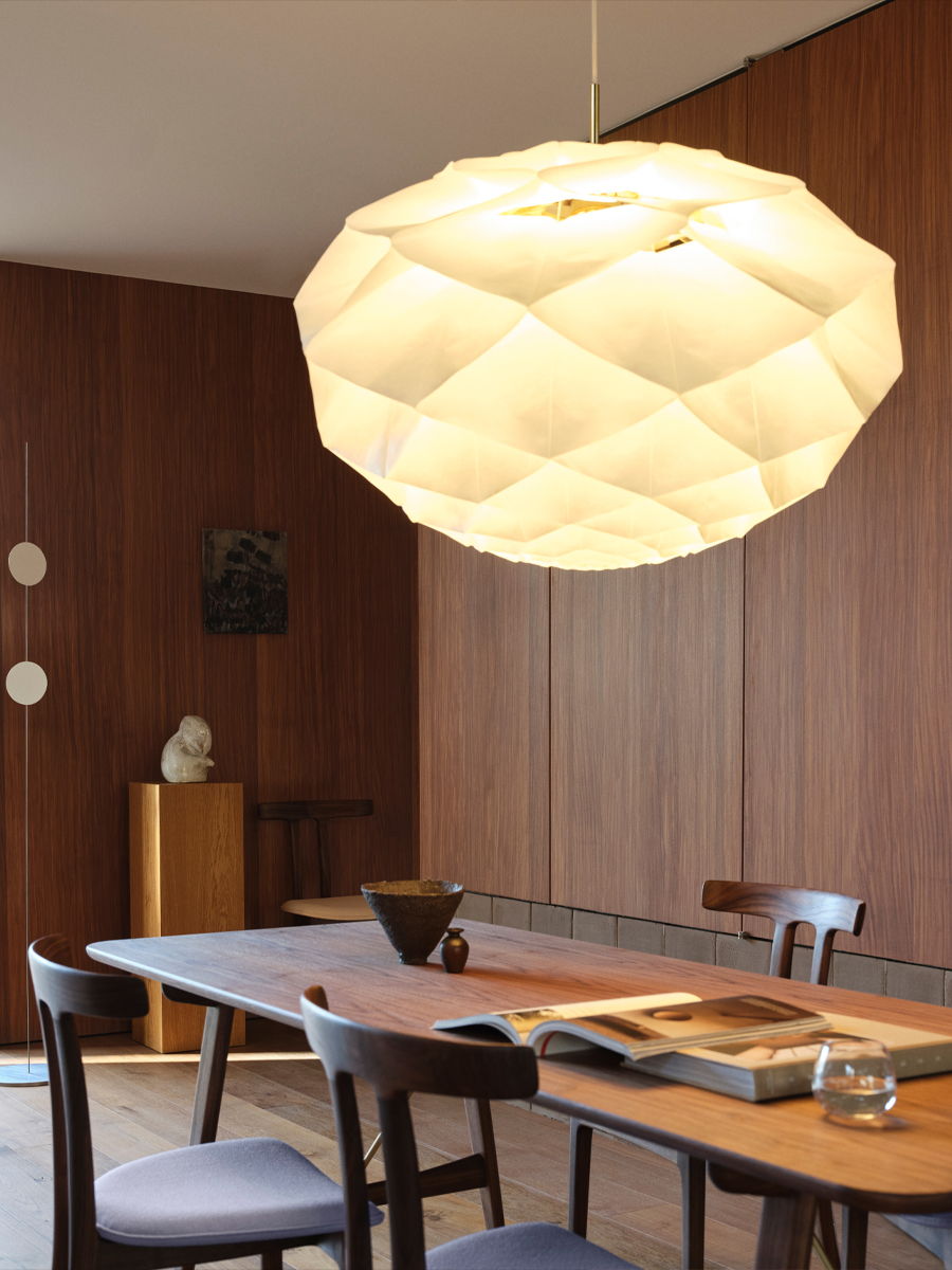 A modern dining area with a geometric pendant lamp and wooden furniture.