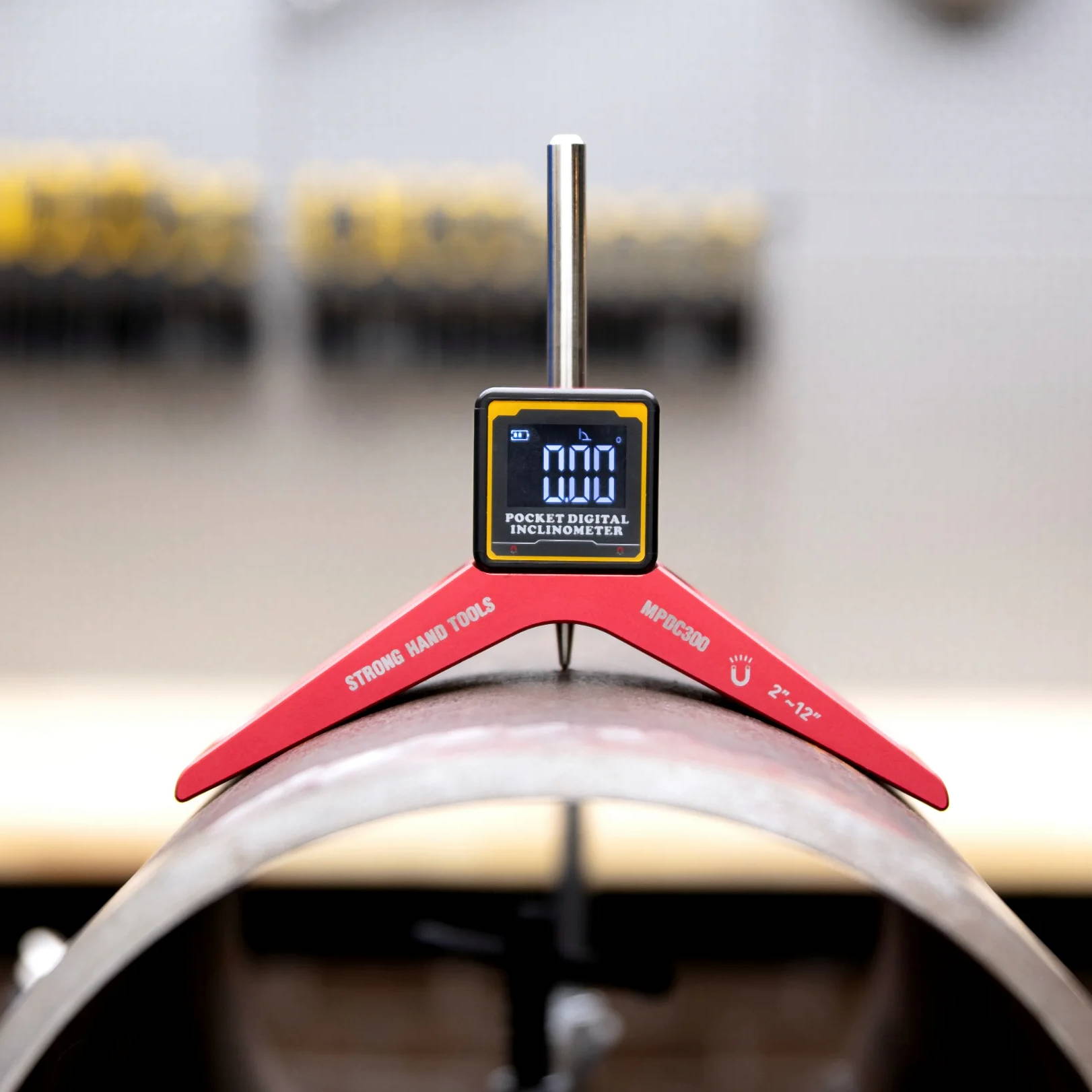 Digital angle finder positioned on a metal pipe for measurement.