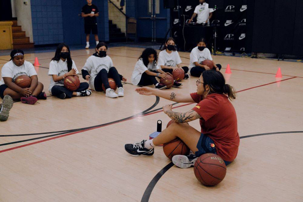 women teaching kids how to play basketball